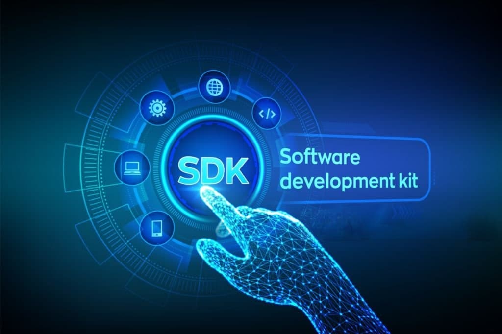 A glowing wireframe hand pressing an SDK button surrounded by icons for platforms and code, illustrating a software development kit.